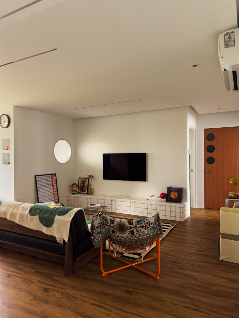 Wide shot of the Bauhaus-inspired living area with tiled console, graphic rug, and mix of retro-inspired props, creating a balanced composition.